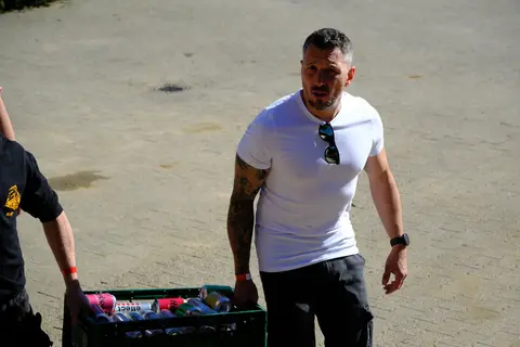 Ein Gast trägt eine Getränkekiste über den Hof