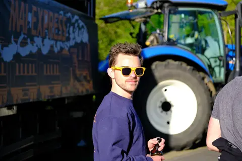 Ein Gast vor dem Traktor neben dem Wagen
