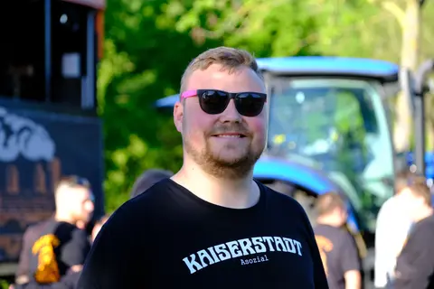 Ein Gast lächelt vor dem blauen Traktor