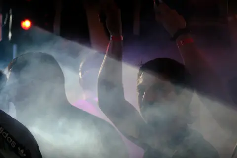 Feiernde Gäste in Nebel und Licht