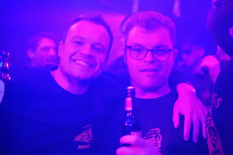 Zwei Gäste lächeln im violetten Licht
