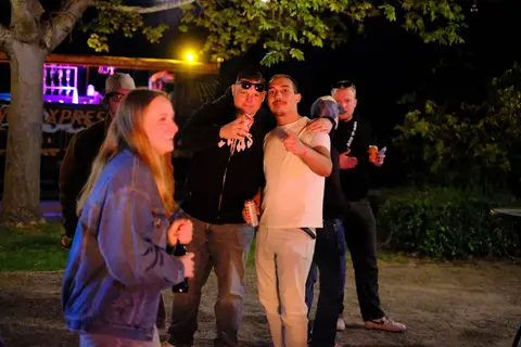 Eine Gruppe posiert nachts vor dem Wagen