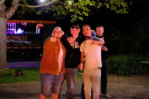 Eine Gruppe mit Handzeichen vor dem Wagen